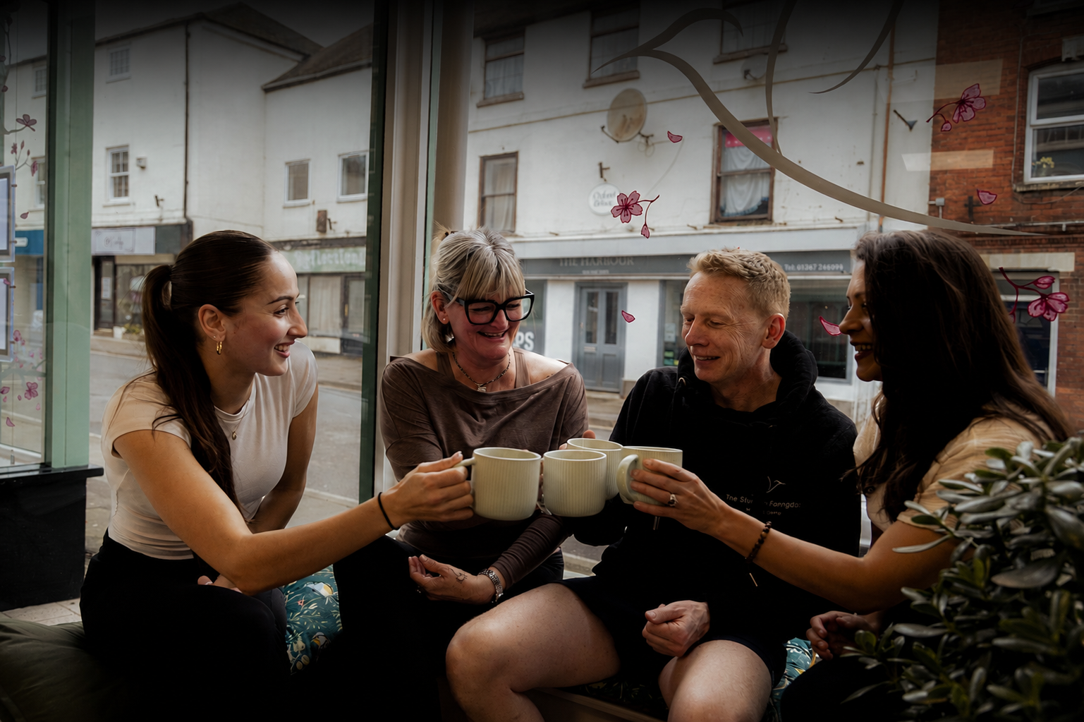 Yoga community members enjoying tea and conversation together in a warm and welcoming wellness studio café space.